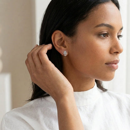 Model draagt zilverkleurige Aramat Jewels Hamsa oorstekers van RVS in de vorm van een Handje van Fatima.