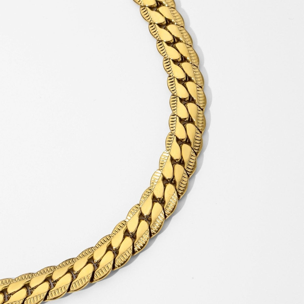 Aramat Jewels platte gourmet ketting van 6mm breed goudkleurig staal met een unieke bewerkte rand voor een luxe look.