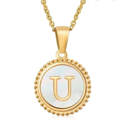 Vergulde hanger met de letter ’U’ op een parelachtige ronde schijf met kralenrand.